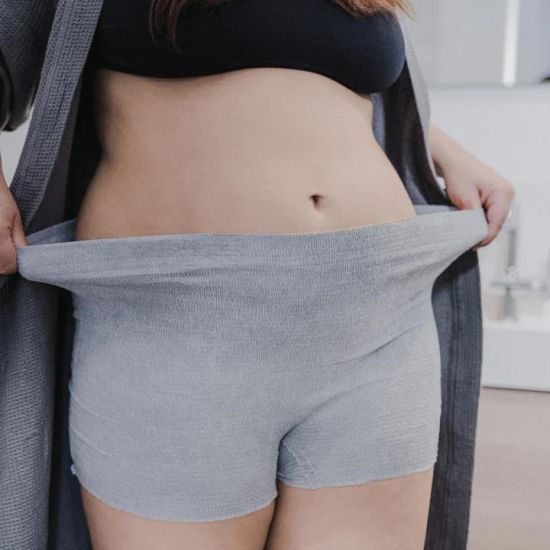 Woman stretching out the waist band of her shorts