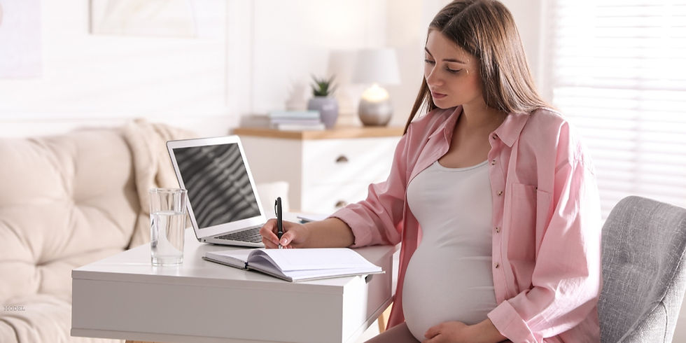 A pregnant woman sitting at a desk with a laptop (model)