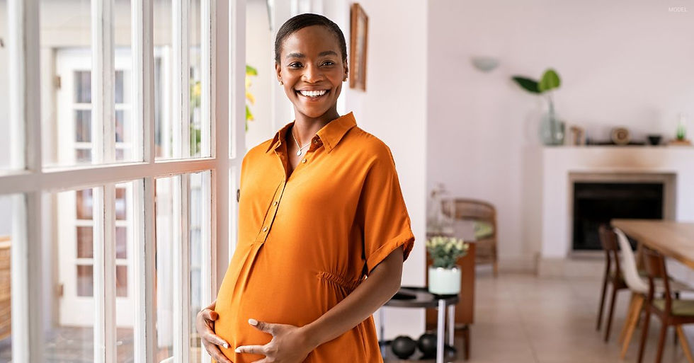 Pregnant woman in orange, holds her stomach and smiles.