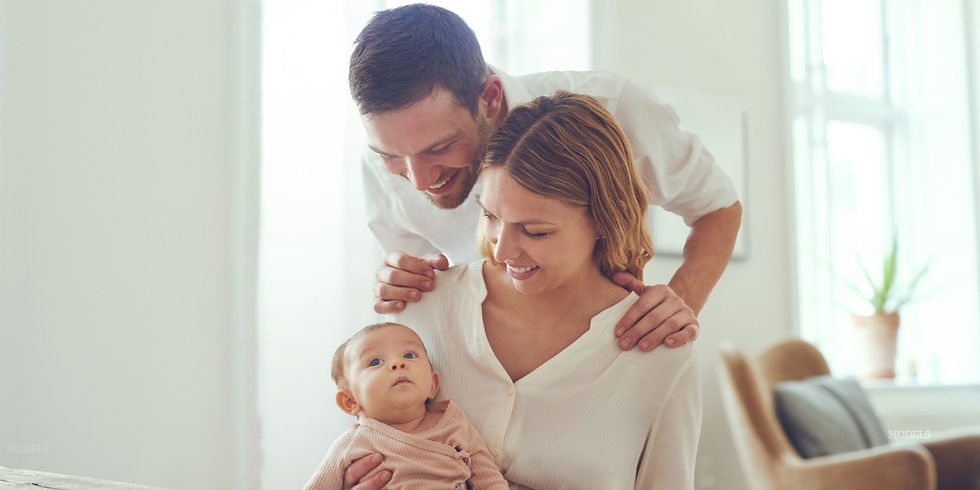 Woman and men holding a baby in a living room (models)
