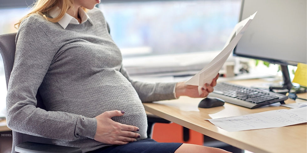 A pregnant woman is sitting at a desk with a piece of paper (model)