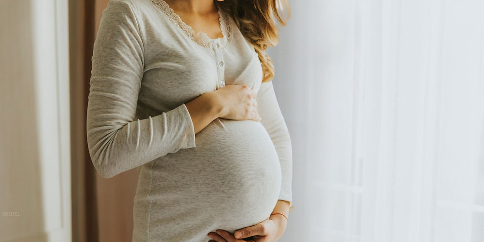 A pregnant woman holds her stomach (model)