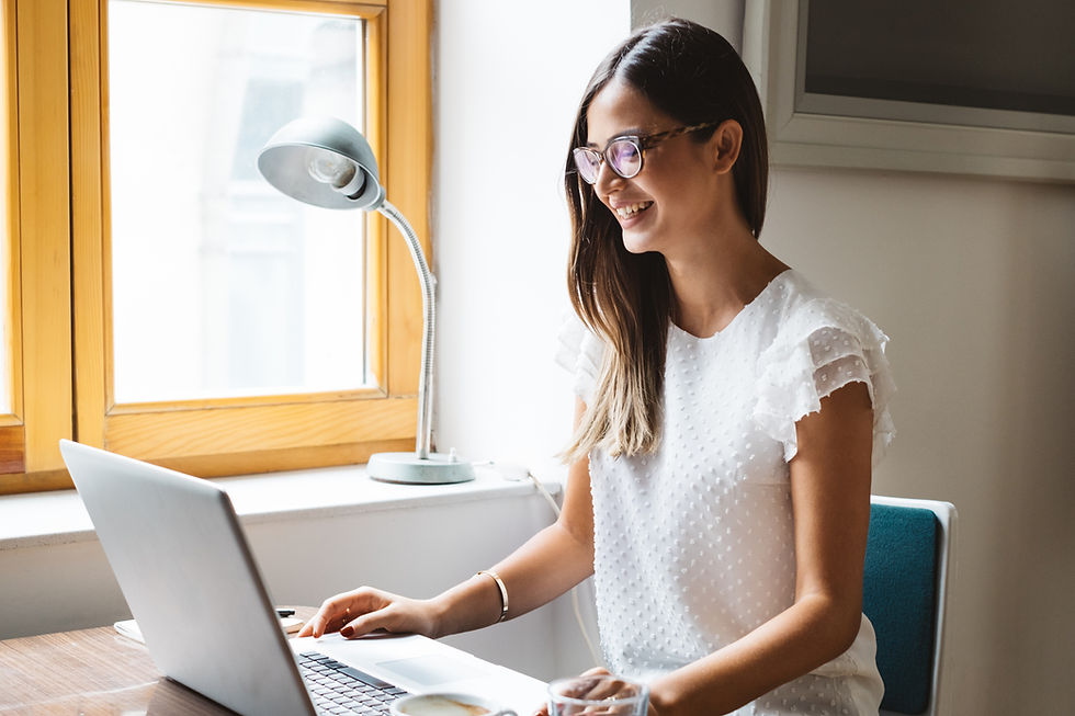 Brunette woman wearing glasses smiling at her laptop