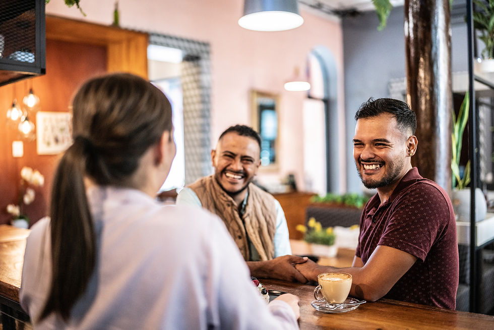 Happy gay couple talking to a woman while having coffee