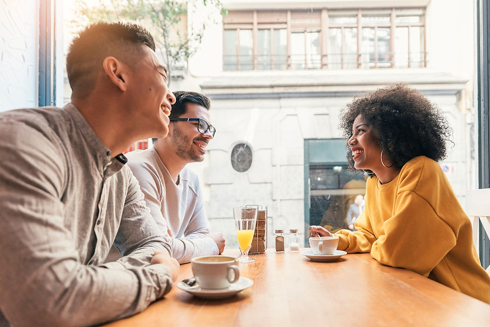 Three adults chatting at a table with coffee and juice