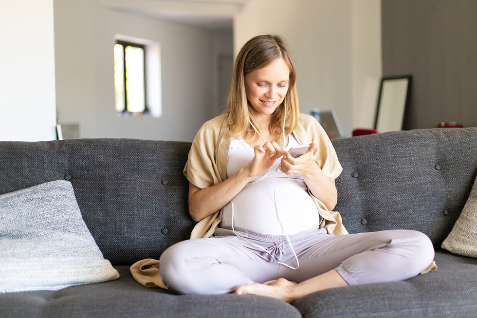 Pregnant woman sitting on the couch listening to music