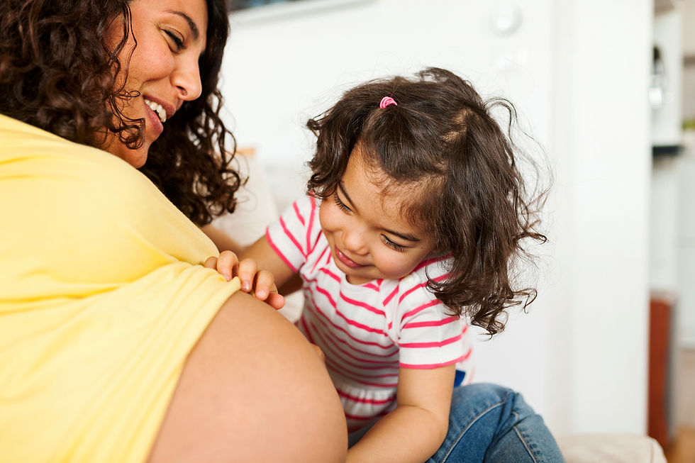 Happy toddler touching her Mom's pregnant belly.