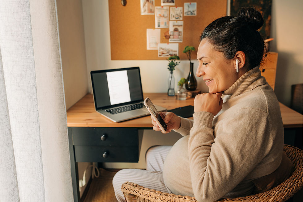 Happy expecting mother video-chatting over the phone at her desk