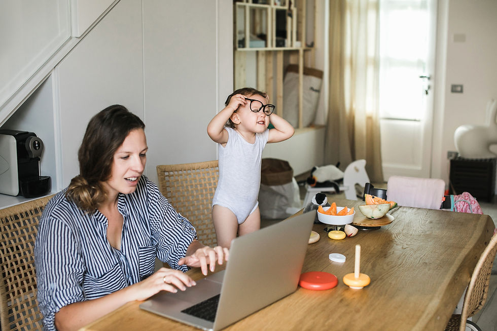Mom working on her laptop next to a toddler wearing glasses