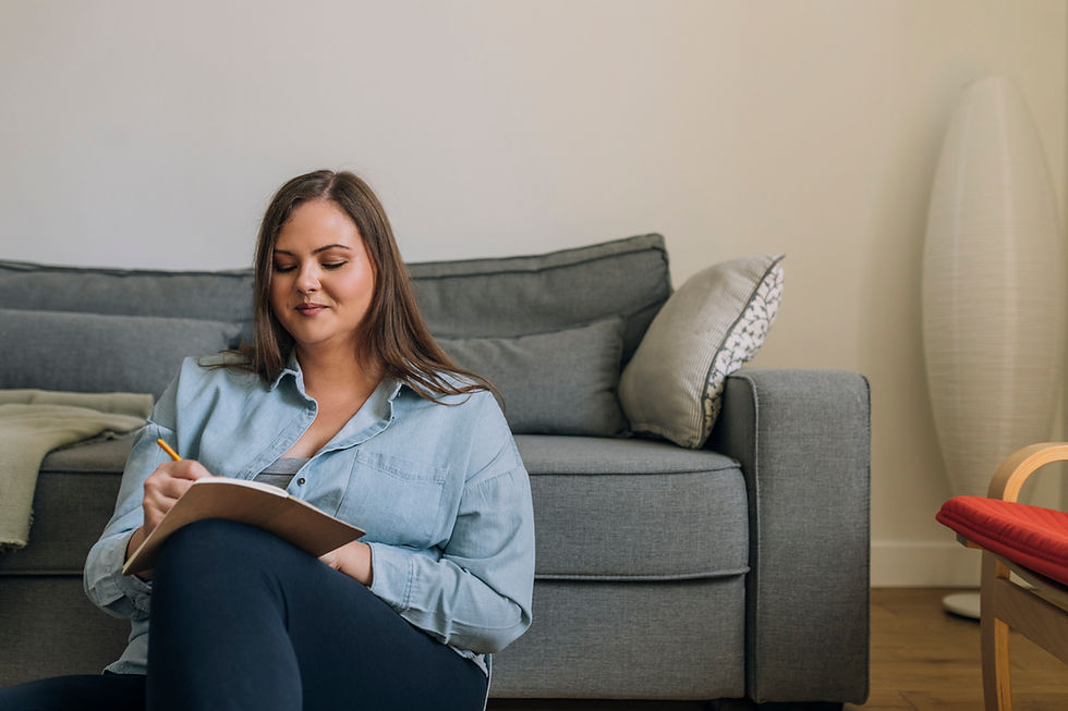 Woman sitting on the ground while writing in a journal