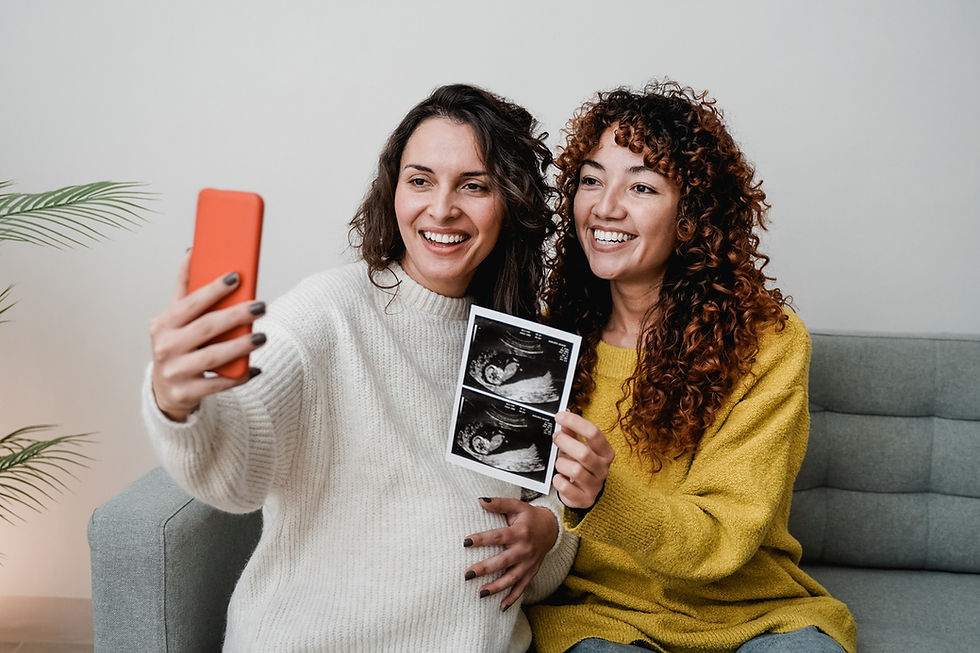 Two smiling women taking a selfie while holding up an ultrasound photo