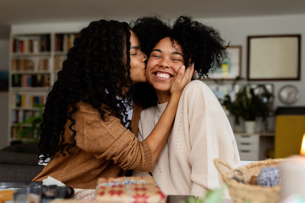 Woman kissing smiling woman's cheek.